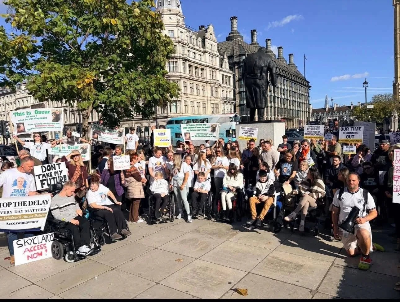 A large group of campaigners, several in wheelchairs, gathered in Parliament Square beneath the Churchill statue, holding placards reading Skyclarys Access Now, Stop the Delay, Don't Take My Future and Time Is Running Out