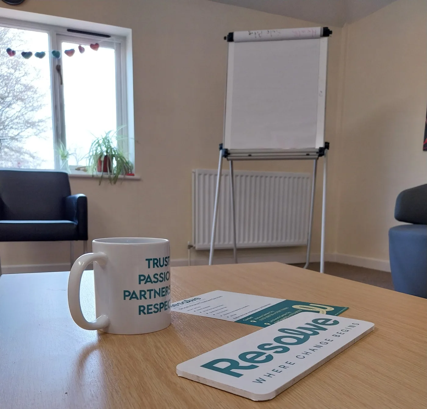 A group room at Resolve with a flip chart, chairs, and a Resolve mug and sign on a table