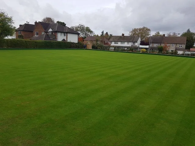 The bowling green at Whitethorn Bowls Club with houses behind the hedge