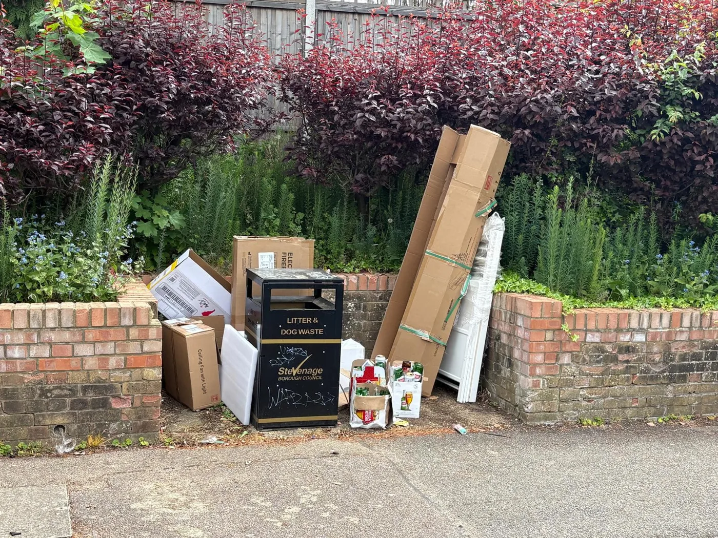 Boxes, bottles and packaging dumped around a litter bin in Torquay Crescent, Stevenage
